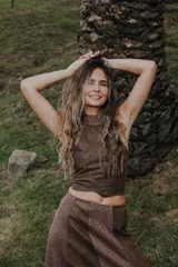 Top corto marrón de cuero sintético con cuello halter y diseño irregular.