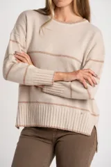 Sweater de lana con cuello redondo y diseño a rayas horizontales en tonos beige y marrón claro. Presenta un calce oversize y puños y ruedo acanalados.