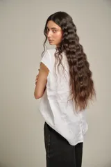 Blusa blanca de lino con cuello redondo, mangas cortas y canesú con alforzas en el frente.