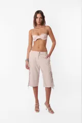 Conjunto de top y short color beige confeccionado en tela brillante. El top cuenta con arco metálico en el busto, tiras para atar en el hombro y ganchos lenceros en la espalda. El short es de tiro alto con cintura elastizada y bolsillos laterales.