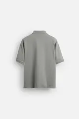 Polo gris de punto con cuello solapa y cierre frontal de cremallera. Corte regular fit, manga corta y acabados en rib.