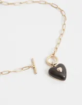 Collar corto con cadena dorada y dije de corazón esmaltado color rosa.