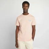 Camiseta rosa pálido de manga corta con cuello redondo y estampado pequeño en el pecho con la palabra "Oranges".