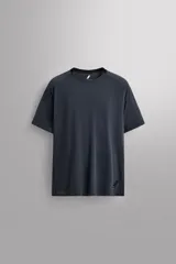 Camiseta deportiva gris oscuro de cuello redondo y manga corta, confeccionada en tejido elástico con estructura. Tiene bajo con aberturas laterales y logo estampado en el bajo.