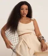 Blusa cropped de sastrería color beige, con escote corazón, breteles anchos con aros metálicos y cierre en la espalda.