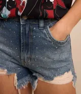 Short de jean de tiro alto, color azul denim, con desgarros, bajo deshilachado y detalles de strass.