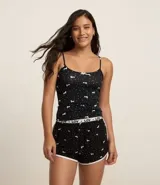 Musculosa de pijama confeccionada en microfibra color negro con estampa de lunares y perritos blancos. Tiene breteles finos fijos y picueta en el escote.