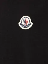 Camiseta negra de algodón con cuello redondo y logo de la marca bordado en el pecho.