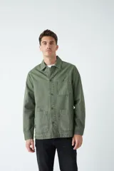 Sobrecamisa verde militar de algodón grueso tipo canvas, con cuello clásico, cierre frontal con botones, dos bolsillos de parche en el pecho con solapa abotonada y dos bolsillos de parche en la parte inferior.