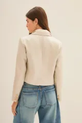 Saco corto color beige confeccionado en lino, con forro de poliéster y viscosa. Presenta solapas de muesca, cierre con un botón y corte cropped.