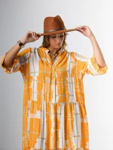 Vestido midi de corte amplio con estampado abstracto en tonos azules, blancos y beige. Tiene cuello en V, mangas 3/4 con volados y corte escalonado en la falda.