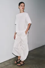 Top de lino color blanco, con cuello redondo y mangas cortas. Detalle de abertura en la espalda ajustable con lazadas.