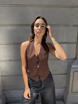 Chaleco marrón con escote halter y cierre frontal con botones.