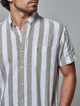 Camisa de hombre de manga corta, confeccionada en lino con rayas verticales blancas y ladrillo. Tiene cuello abotonado y bolsillo en el pecho.