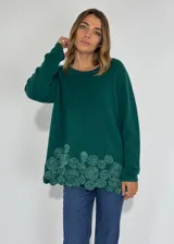 Sweater de color verde con detalles de rosas en la parte inferior, de manga larga y corte holgado.