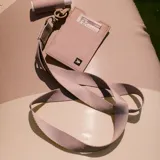 Llavero tipo lanyard de tela tejida color beige, con gancho metálico y detalle de pieza de cuero sintético con logo grabado.