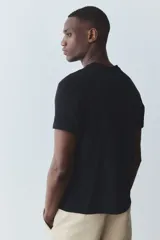 Remera negra de corte estándar con cuello redondo ribeteado y bajo recto. Confeccionada con tejido funcional COOLMAX®, una fibra de poliéster de secado rápido que elimina la humedad y regula la temperatura corporal.