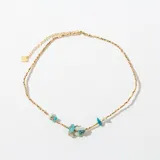 Collar de cadena dorada con pequeñas piedras semipreciosas de tonos turquesa y celeste, dispuestas en el centro.