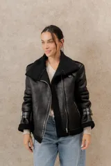 Chaqueta gamulan negra de ecocuero con interior de corderito sintético, cierre lateral asimétrico, cuello con solapas y bolsillos con cierre.