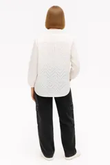 Camisa blanca de algodón con pequeños calados, de corte holgado y manga larga.