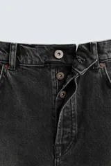Pantalón de jean negro con efecto lavado, corte slim fit, cinco bolsillos y cierre frontal con botones.