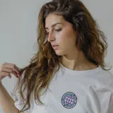 Remera blanca de algodón con estampa circular en la espalda con un globo terráqueo en color lila y texto "Bad Decisions Club Member" en negro y celeste.