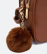 Bolso bandolera pequeño de cuero sintético negro con doble compartimento con cierre de cremallera dorada, asa corta y correa larga ajustable. Incluye pompón decorativo.