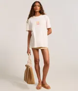 Remera alargada de algodón color crema con estampa de palmeras y atardecer en la playa.
