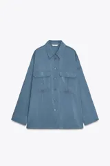 Camisa rosa claro confeccionada en hilatura con modal, de corte holgado, con cuello solapa, manga larga terminada en puño, dos bolsillos con solapa en el delantero y cierre frontal con botones.