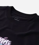 Remera negra de algodón con cuello redondo y mangas cortas. Presenta un estampado frontal con la frase "Divine Spark" y un estampado grande en la espalda de un ángel con halo y rayos celestes.