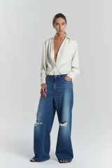 Pantalón denim bootcut de corte holgado, con roturas en las rodillas y tiro alto.