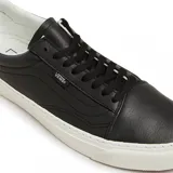 Championes Vans Old Lux negros de cuero con suela blanca.