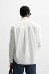 Camisa azul marino de algodón con textura jacquard, corte relaxed fit, cuello solapa, manga larga con puños abotonados y cierre frontal con botones.