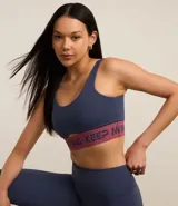 Top deportivo azul con breteles anchos, copas desmontables, recorte cutout en el busto y cintura elástica con estampa lettering Keep Moving.