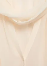 Blusa color crema de mangas largas abullonadas, con lazo en el cuello y tejido semitransparente.