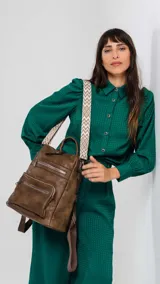 Mochila negra de símil cuero con apertura superior y tres bolsillos frontales con cierres metálicos. Incluye bolsillos laterales y tres bolsillos internos. Tiene correa larga de galón regulable para usar como bandolera y correas para colgar en la espalda.