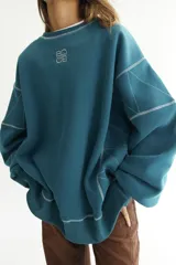 Buzo azul petróleo de felpa de algodón con pespuntes en zigzag blancos y logo bordado en el pecho.