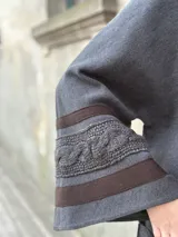 Saco tipo capa color gris de tejido de punto fino en lana con detalles de cintas tejidas y trenza.