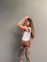 Cartera bandolera de cuero color marrón, con correa ajustable y bolsillo externo con cierre.