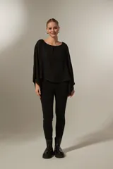 Blusa negra holgada de poliéster con mangas largas y cuello redondo.