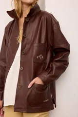 Chaquetón de cuero negro oversized, con corte recto y bolsillos delanteros. Presenta un bordado en los bolsillos inspirado en la costa atlántica.