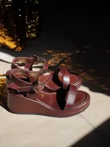 Sandalias de mujer con plataforma, tiras de cuero marrón y hebilla dorada. La plataforma es de color blanco con textura de piel de serpiente.