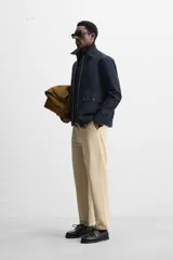 Pantalón color arena de corte recto, confeccionado en tejido de algodón con estructura canvas. Cuenta con cintura ajustable con trabillas laterales, bolsillos frontales y traseros de vivo. Cierre frontal con cremallera y botón.