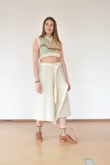 Falda midi color beige de corte evasé, con estructura envolvente y caída fluida. Se ajusta con broches a presión metálicos y cinturón de la misma tela.