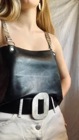 Top negro de cuero con tirantes finos de cuero sintético con argollas metálicas.