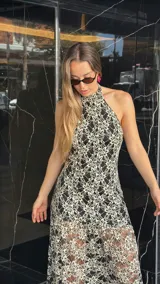 Vestido midi de encaje floral color beige sobre base negra, con cuello halter y falda con vuelo.