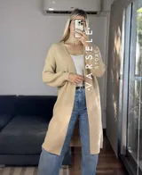 Cárdigan largo color beige, de tejido de punto grueso, con mangas largas abullonadas.