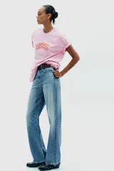 Camiseta rosa de algodón con efecto lavado, corte regular, cuello redondo y mangas cortas. Estampado frontal con la frase "Puerto Rico Vuela Conmigo".