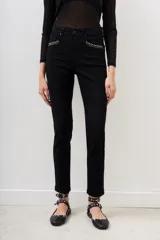 Pantalón jean negro de corte slim con detalles de tachas plateadas en los bolsillos delanteros y en el ruedo.