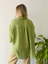 Camisa verde de lino, corte amplio y largo, con cuello clásico y mangas largas.
